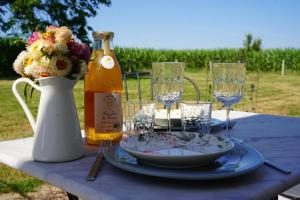a table with a bottle of wine and plates and glasses at Le loft d'Adrien, une ode à la douc'Eure, classé 3 étoiles, accueil vélo in Beauficel-en-Lyons