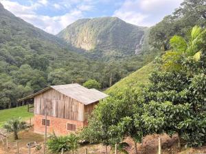 a barn on a hill with mountains in the background at Recanto Salto Ano Bom in Corupá