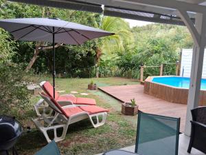 a patio with a chair and an umbrella and a pool at villa Kanel in Le Robert