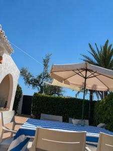 a table and chairs with an umbrella and palm trees at Villa Gabriela in S'Algar