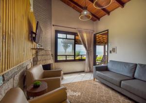 a living room with a couch and chairs and a window at Village Praia do Rosa in Praia do Rosa