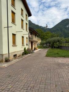 a brick road next to a building with mountains in the background at Bike & Bikers Hotel and Restaurant in Ampezzo