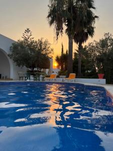 a swimming pool with a sunset in the background at La Baïa Cozy in Sukrah
