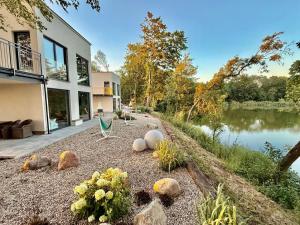 a house with rocks on the ground next to a lake at ENKLAWA IMPERIUM- DOM WAKACYJNY-APARTAMENTY NAD JEZIOREM- 20 km od TORUNIA-PLAŻA,JACUZZI 