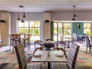 a dining room with tables and chairs and windows at Novotel Newcastle Airport in Newcastle upon Tyne