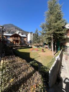 a park with a tree and some buildings at New Daffodil Classic Manali in Manāli
