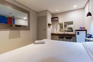 a bedroom with a white bed and a kitchen at Soft Motel - USP in São Paulo