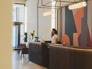 a woman standing behind a counter in an office at BYPILLOW Grand Central in Padova