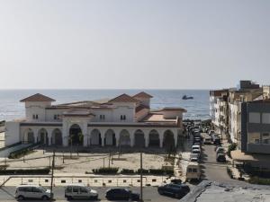 a building with cars parked in front of the ocean at Younes résidence 2 in Asilah