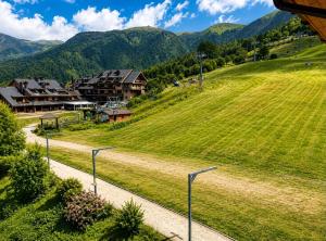 a grassy hill with houses and mountains in the background at La Splaza Home in Pian Camuno
