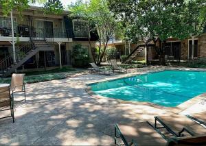 a swimming pool in front of a building with chairs at Healing Haven King Bed Suite in Dallas
