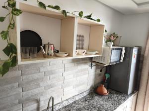 a kitchen with a brick wall with a microwave and a refrigerator at Younes résidence 2 in Asilah +19 photos
