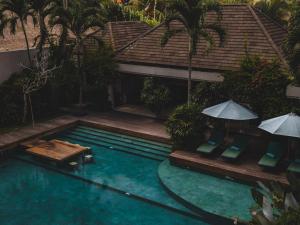 a swimming pool with chairs and umbrellas next to a house at The Hidden Paradise Ubud - CHSE Certified in Ubud
