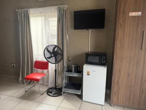 a room with a refrigerator and a fan and a window at Nkandla Yethu Guest House in Nelspruit