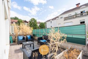 a patio with couches and tables on a balcony at Duplex Le G - Reine des neiges 10 min Disney Paris in Montévrain