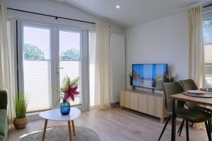 a living room with a television and a table and chairs at Ostseecamp Ferienhaus "KleineDüne" in Scharbeutz