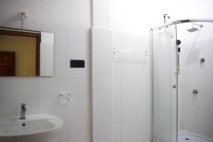 a white bathroom with a shower and a sink at Palm Beach Resort in Trincomalee