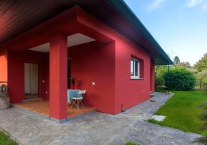 a red house with a table on a patio at Maison Rouge in Besnate