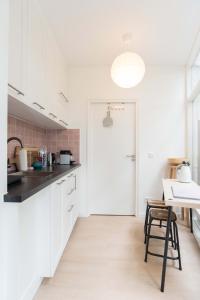 a kitchen with white cabinets and a table and a door at B&B Amsterdam West in Amsterdam +11 photos