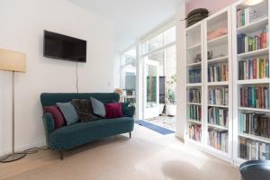 a living room with a green couch and book shelves at B&B Amsterdam West in Amsterdam