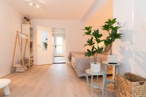 a living room with two potted plants and a bed at Studio Loet in Schagen