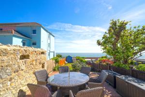 a patio with a table and chairs and the ocean at Jan Dee Cottage in Ventnor