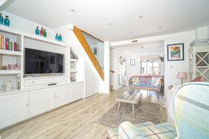 a living room with white cabinets and a tv at Jan Dee Cottage in Ventnor