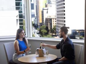 a man and a woman sitting at a table with wine glasses at Novotel Perth Langley in Perth