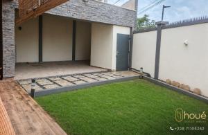 a backyard with a lawn in front of a building at Résidence Houé in Lomé