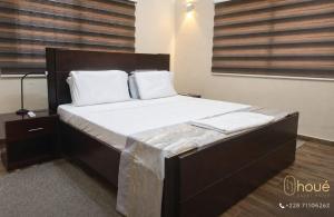 a bedroom with a large bed with white sheets and pillows at Résidence Houé in Lomé