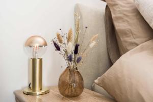 a vase of flowers on a table next to a lamp at Ben Thuis Studio Alkmaar in Alkmaar