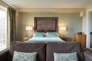 a bedroom with a bed with two chairs and two lamps at Landal Whitbarrow in Penruddock +23 photos