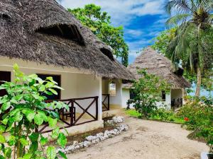 two thatched cottages with a gate in front at Zuri Sana Beach Hotel in Kepwani