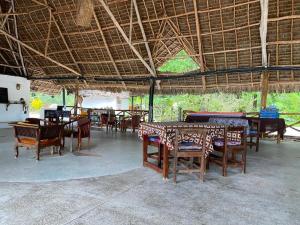 a restaurant with tables and chairs and a large roof at Zuri Sana Beach Hotel in Kepwani