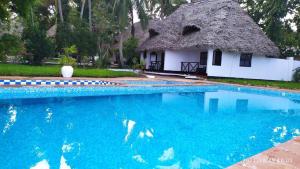 a house with a thatch roof and a swimming pool at Zuri Sana Beach Hotel in Kepwani