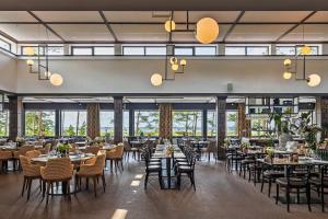 a dining room with tables and chairs and windows at Hotel Riviera Strand in Båstad