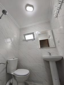 a white bathroom with a toilet and a sink at Younes résidence 2 in Asilah