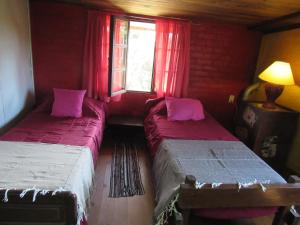 two beds in a room with red walls and a window at Casa de huéspedes cochera cubierta in Oberá +67 photos