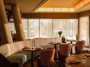 a restaurant with tables and chairs and a large window at RIVELIAN Grand Menorca in Menorca