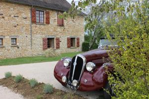 una vecchia auto è parcheggiata di fronte a un edificio di Hôtel Chastrusse a Nadaillac-de-Rouge Altre 7 foto
