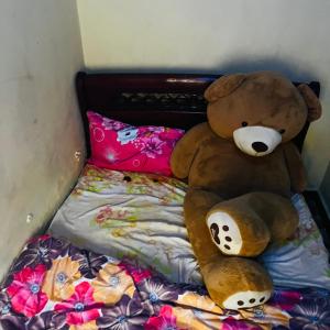 a large brown teddy bear sitting on a bed at Shalompalace in Luanda