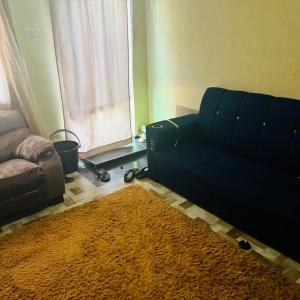 a living room with a blue couch and a rug at Shalompalace in Luanda