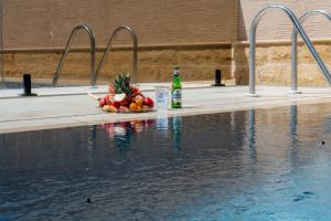 a bottle of beer and a bowl of fruit next to a swimming pool at منتجع ليورا ــ Liora Resort in Al Ḩanī