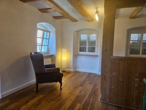 a living room with a chair and two windows at Milchhäusle in Söllingen