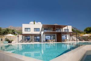 a villa with a swimming pool in front of a house at Zoe Sea View Villas in Paleros