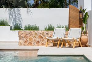 two chairs sitting on a patio next to a swimming pool at Villa Rhodea in Ialysos