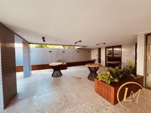 a lobby with tables and chairs in a building at LM One Jardim Oceania in João Pessoa
