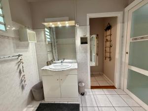 a white bathroom with a sink and a shower at Bungalow Tec-Tec Proche plage et centre Saint Leu in Saint-Leu +4 photos