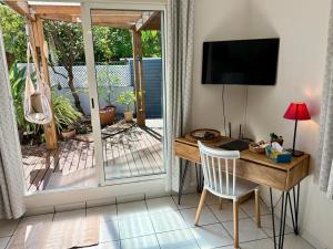 a room with a desk and a television and a sliding glass door at Bungalow Tec-Tec Proche plage et centre Saint Leu in Saint-Leu