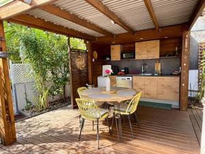 an outdoor kitchen with a table and chairs on a deck at Bungalow Tec-Tec Proche plage et centre Saint Leu in Saint-Leu